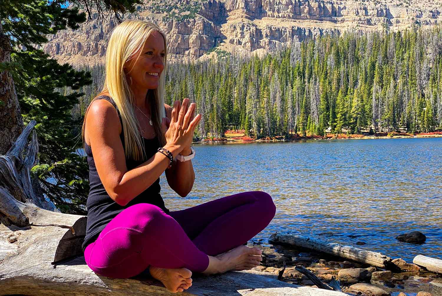 Yoga teacher in relaxing pose at mountain lake in Utah